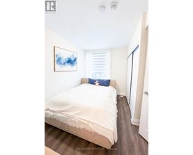 A bedroom with a bed, a painting, and a door.