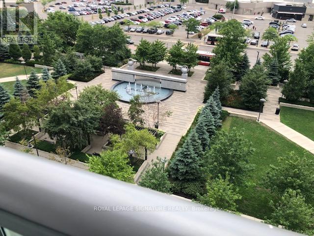 A view from a window looking out at a parking lot and a building with a pool.