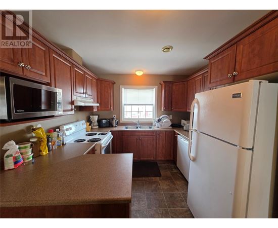 A kitchen with brown cabinets and a white refrigerator.