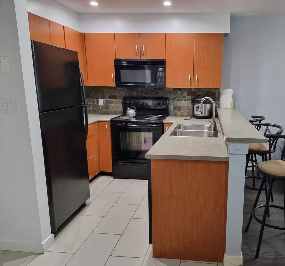 A kitchen with a black refrigerator, black oven, and black microwave.