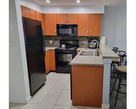 A kitchen with a black refrigerator, black oven, and black microwave.