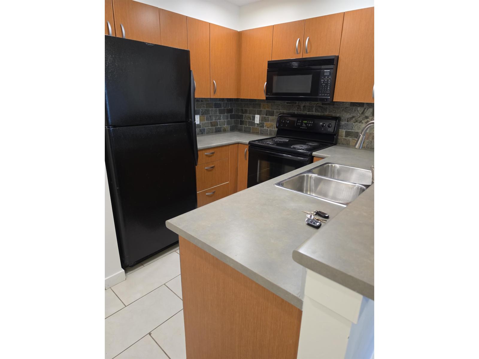 A kitchen with a black refrigerator, microwave, and stove.