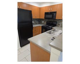 A kitchen with a black refrigerator, microwave, and stove.
