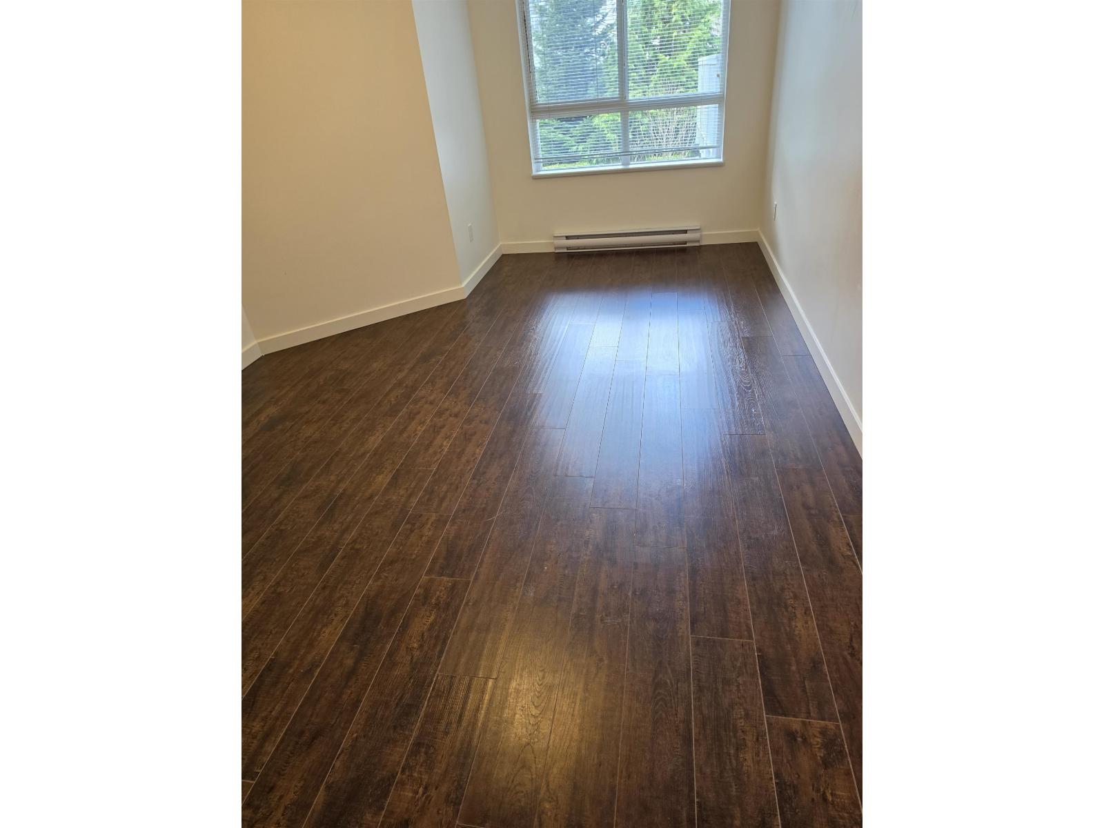 A room with wooden flooring and a window.