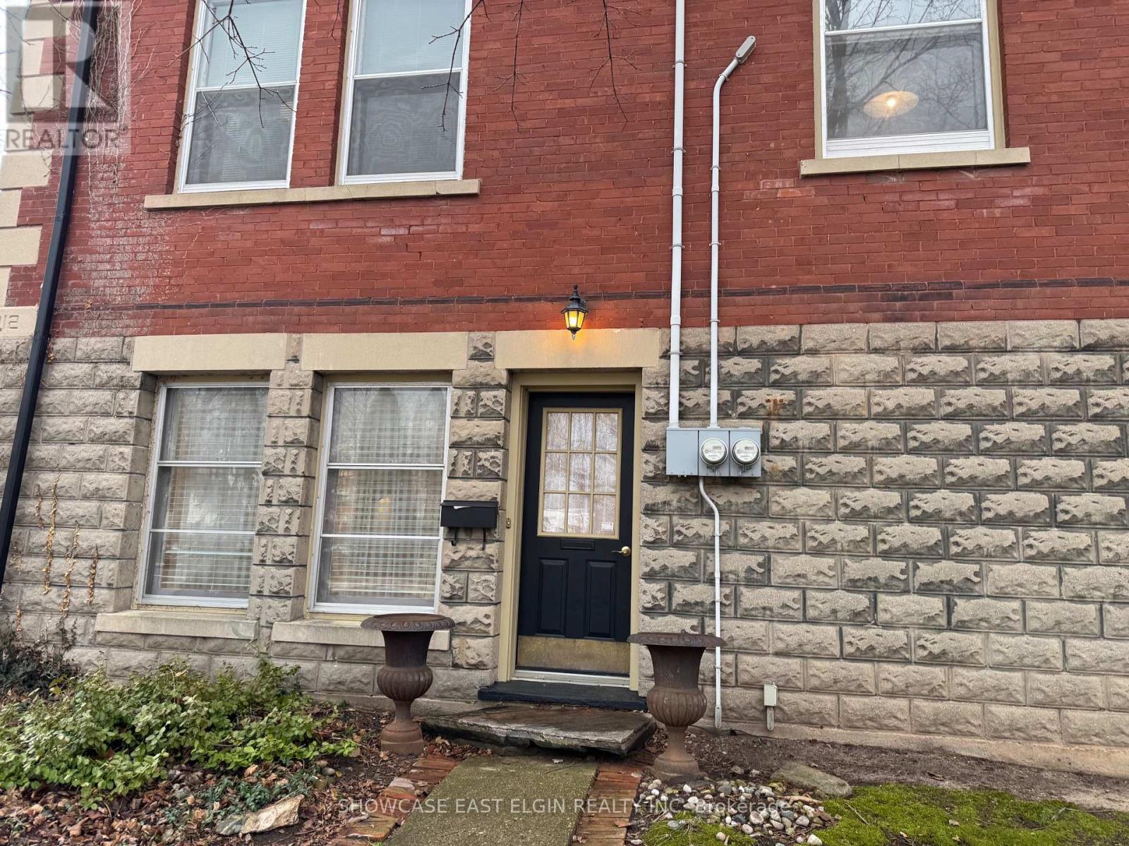A red brick house with a black door and a small window.