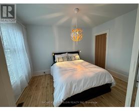 A bedroom with a bed, a chandelier, and a window with curtains.