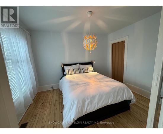 A bedroom with a bed, a chandelier, and a window with curtains.
