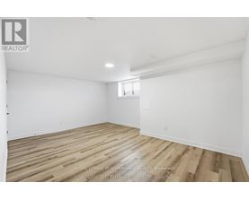A spacious room with wooden flooring and white walls.