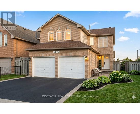 A house with a driveway and garage doors is for sale.