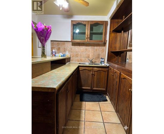 A kitchen with wooden cabinets and a tiled floor.