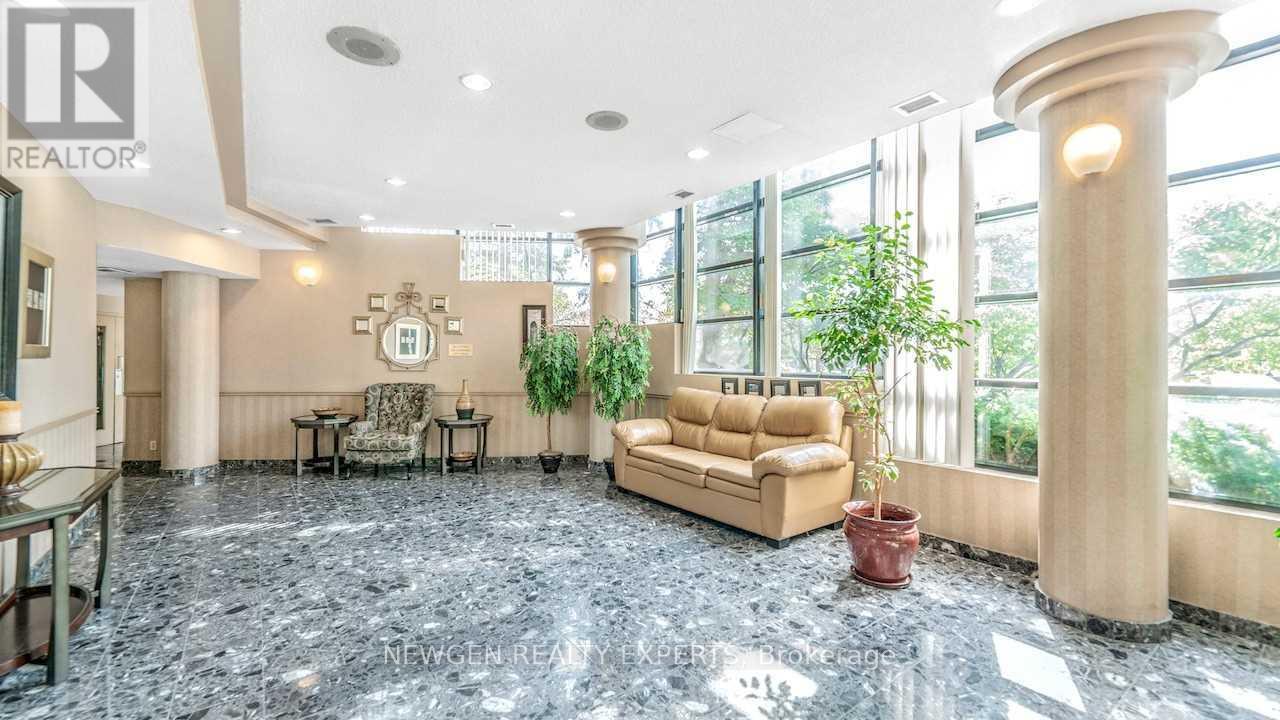 A living room with a couch, chairs, and a potted plant.