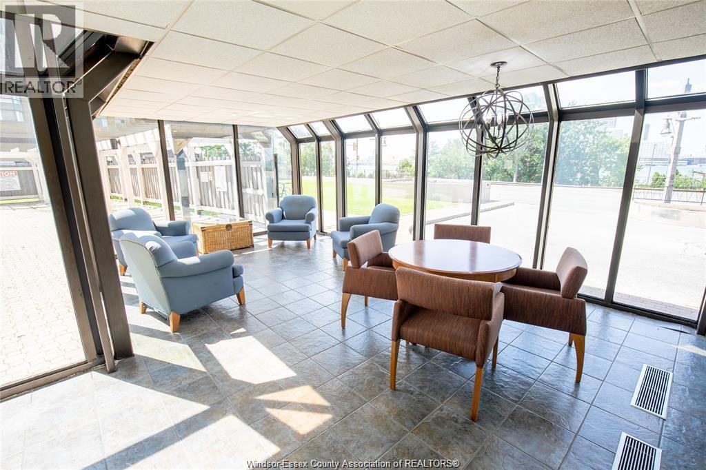A sunny day in a spacious room with a table surrounded by chairs.