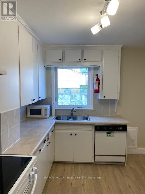 A kitchen with white cabinets and a black counter top.