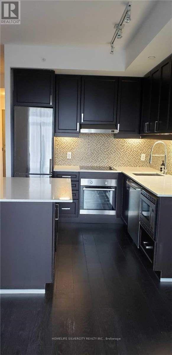 A modern kitchen with black cabinets and stainless steel appliances.