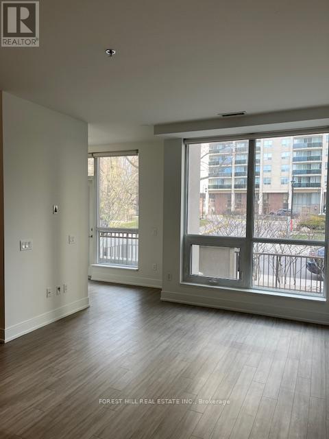 A spacious room with a large window and wooden flooring.