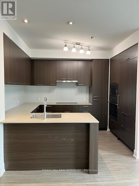 A modern kitchen with dark wood cabinets and a white countertop.