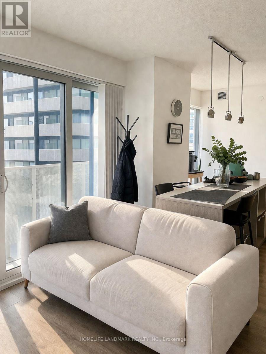 A white couch is in a living room with a black coat hanging on a coat rack.