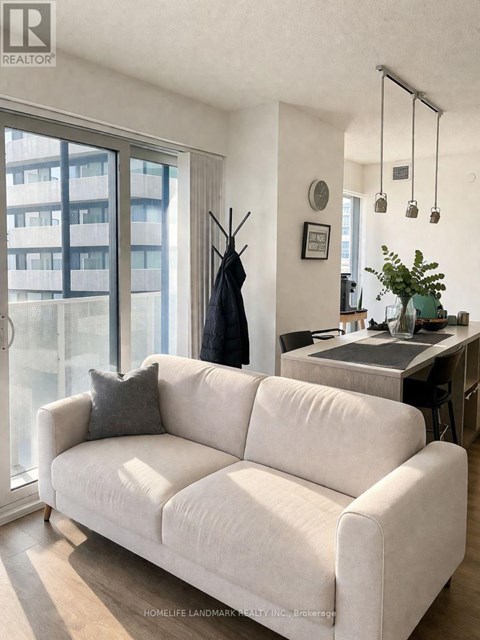 A white couch is in a living room with a black coat hanging on a coat rack.