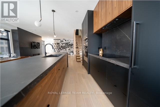 A modern kitchen with wooden cabinets and a staircase in the background.