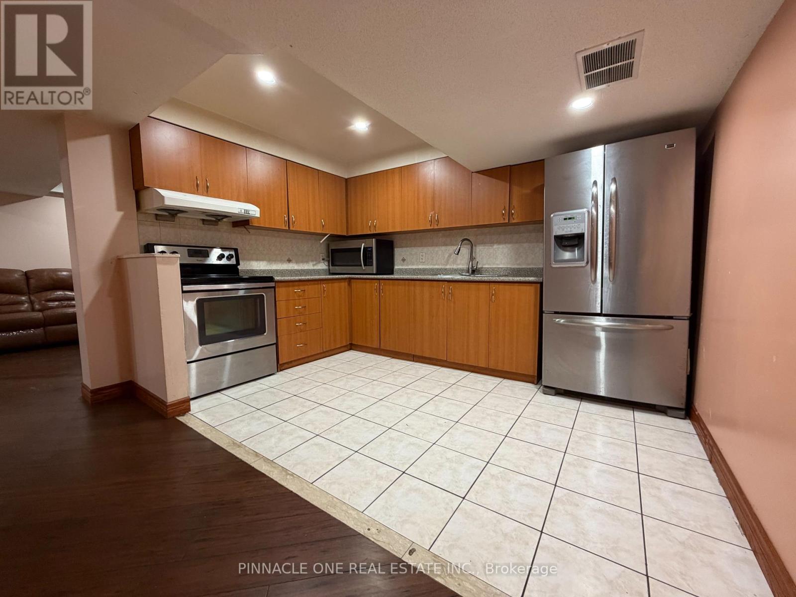 A kitchen with a refrigerator, microwave, oven, and sink.