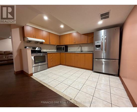 A kitchen with a refrigerator, microwave, oven, and sink.