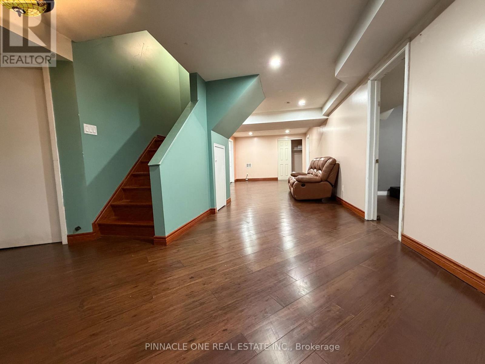 A living room with a brown sofa and a staircase.