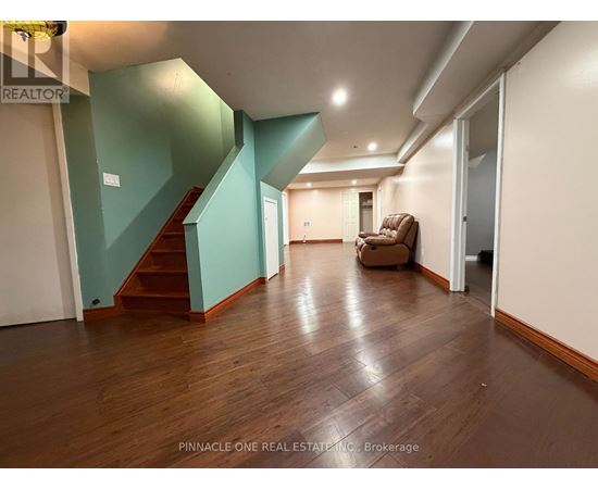 A living room with a brown sofa and a staircase.