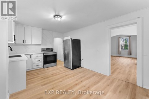 A kitchen with white cabinets and a black refrigerator.
