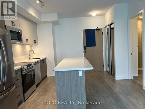 A kitchen with a refrigerator, oven, and microwave.