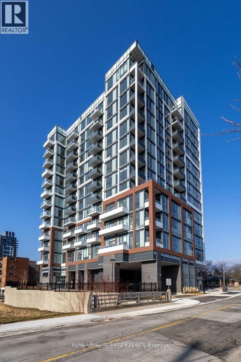 A tall residential building with a glass facade stands under a clear blue sky.