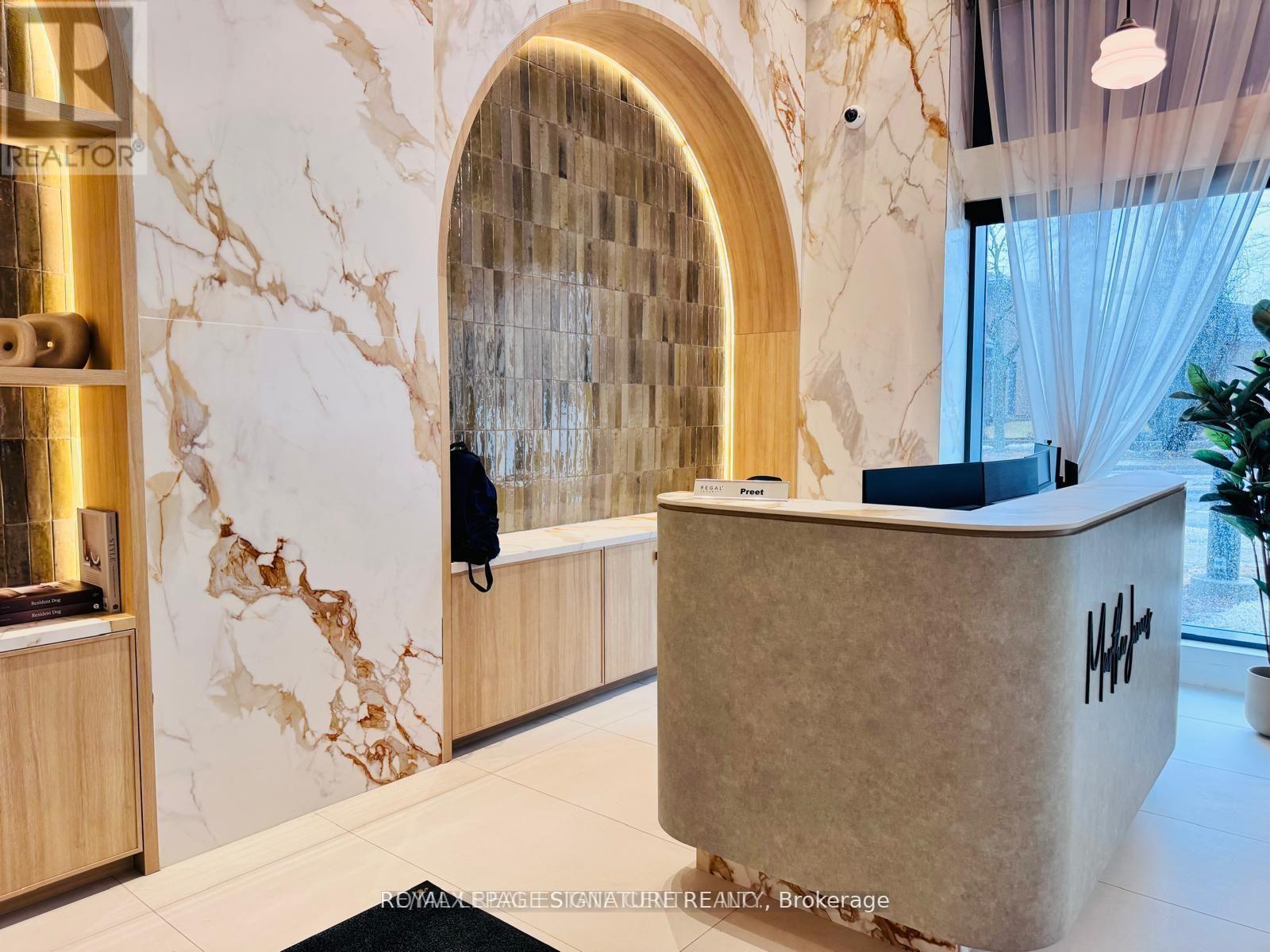 A reception area with a marble wall and a wooden reception desk.