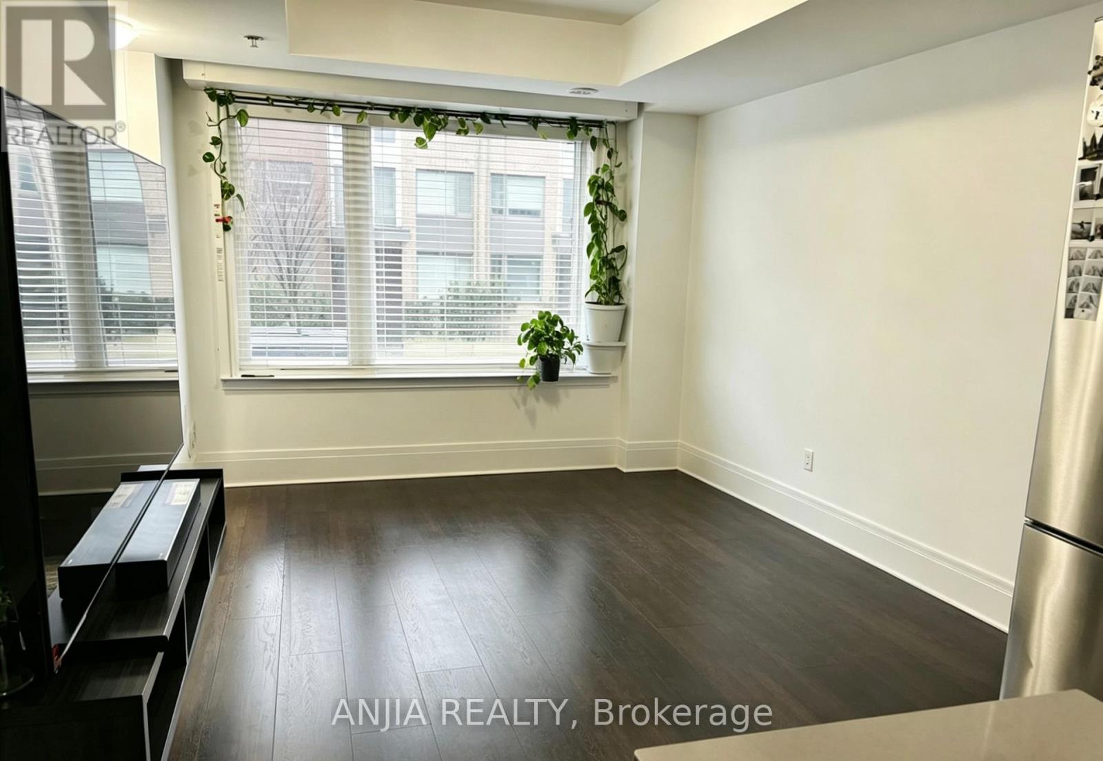 A room with a wooden floor and a window with white blinds.