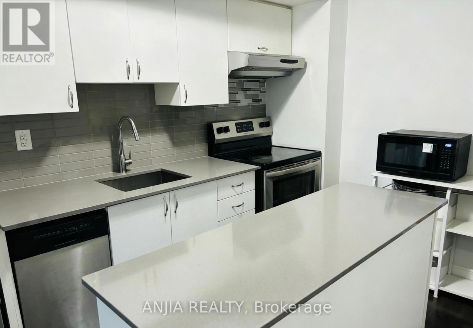 A modern kitchen with white cabinets and stainless steel appliances.