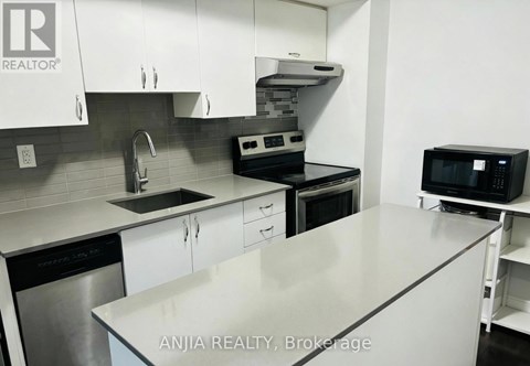 A modern kitchen with white cabinets and stainless steel appliances.