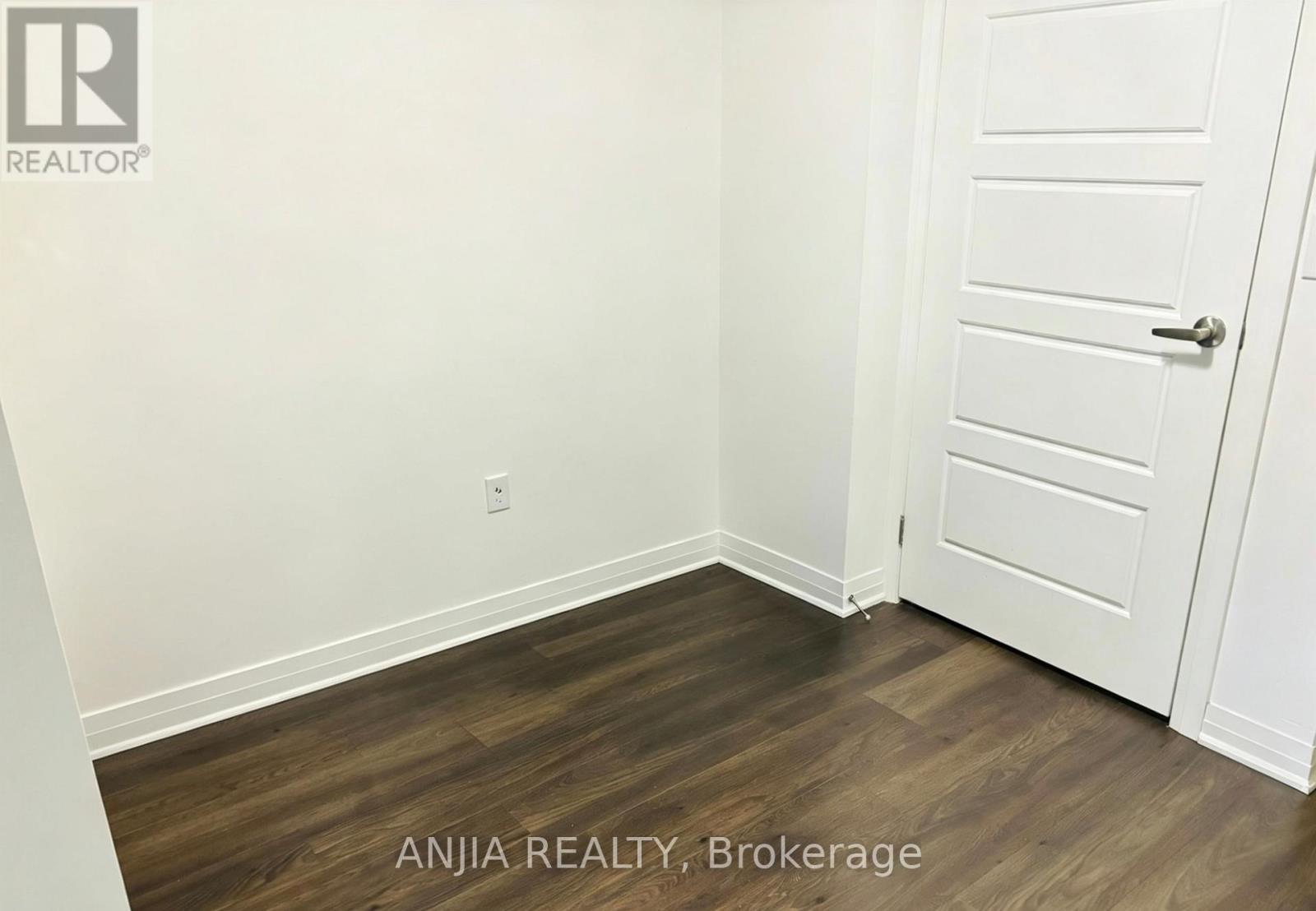 A room with a white door and a wooden floor.