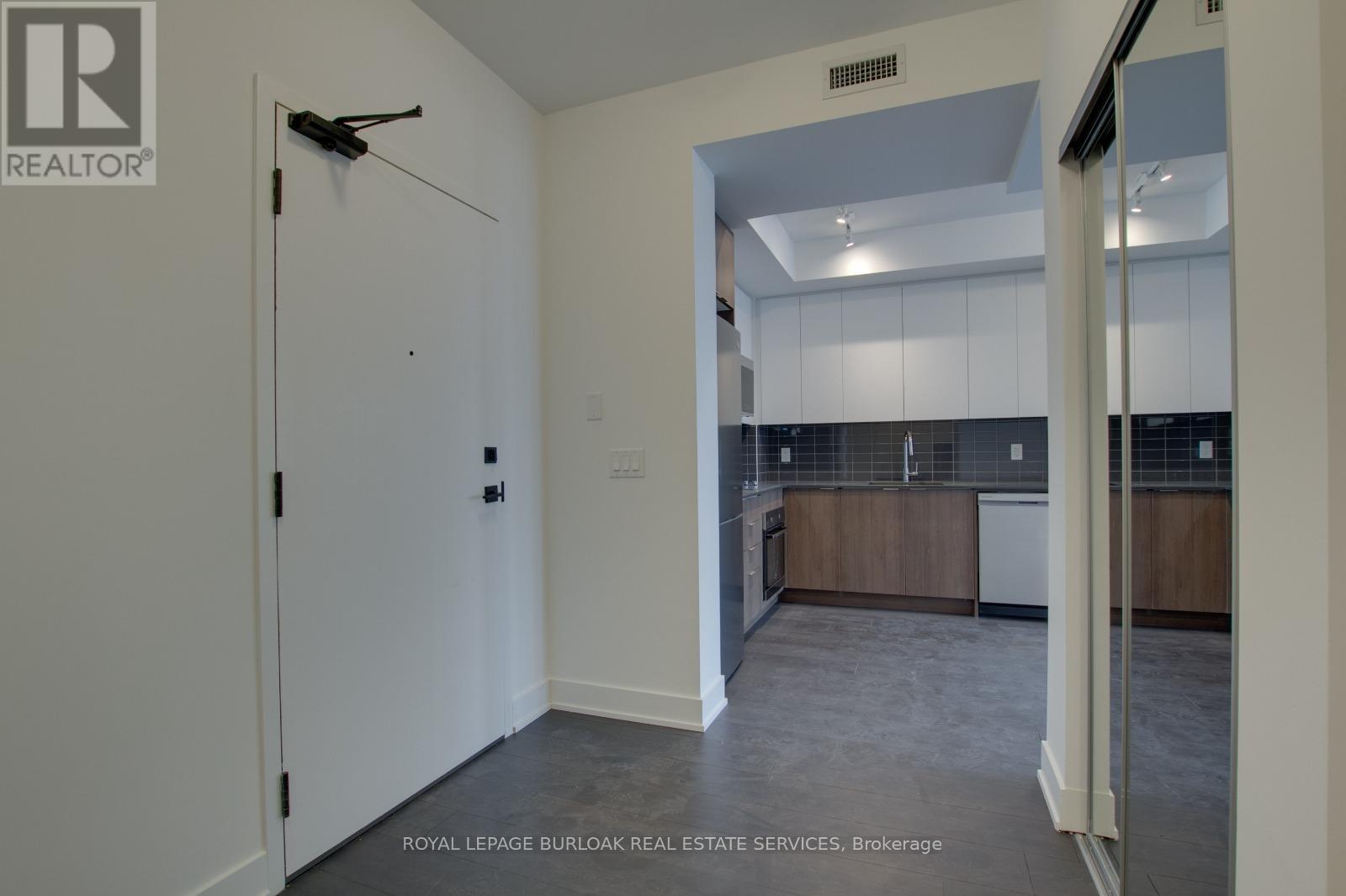 A white door with a black handle is open to a kitchen.