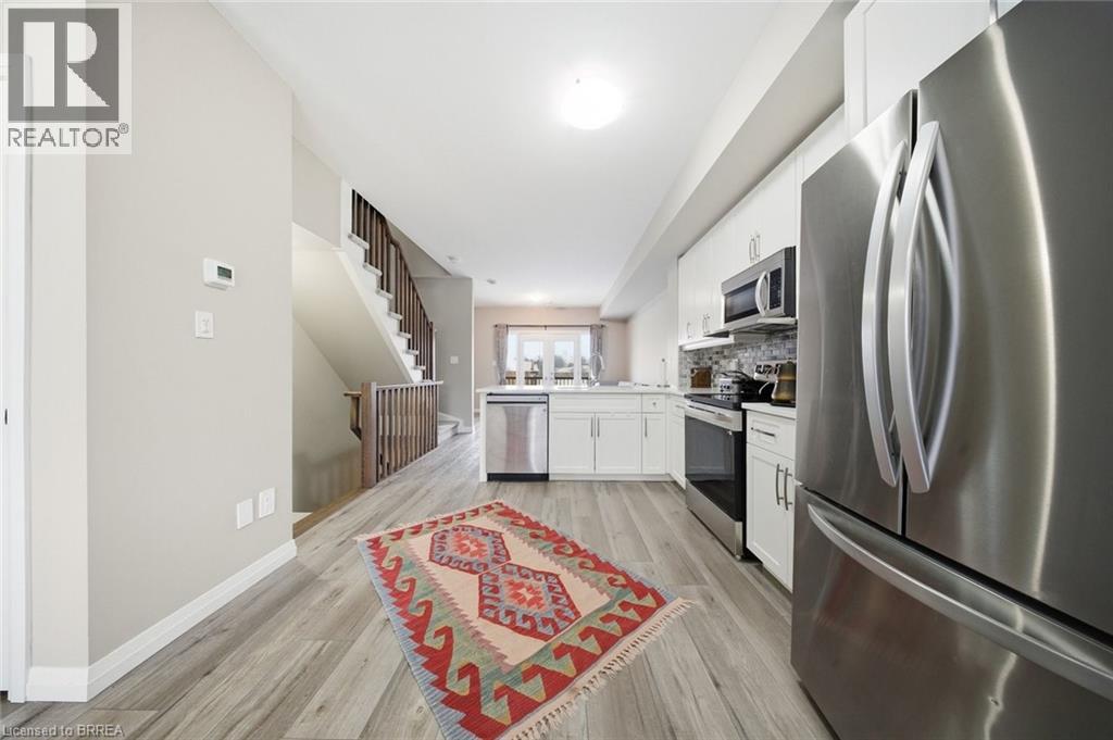 A modern kitchen with a stainless steel refrigerator and a patterned rug on the floor.