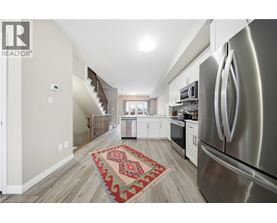 A modern kitchen with a stainless steel refrigerator and a patterned rug on the floor.