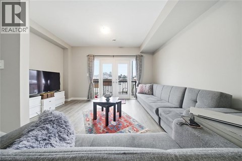 A living room with a grey couch and a red rug.