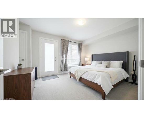 A bedroom with a large bed, a wooden dresser, and a window with curtains.