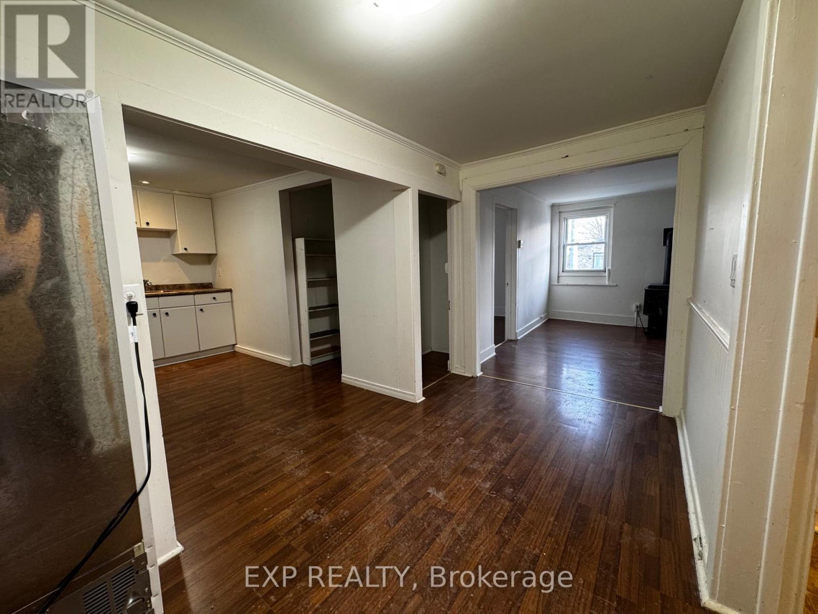 A room with wooden floors and white walls, with a poster on the left side.