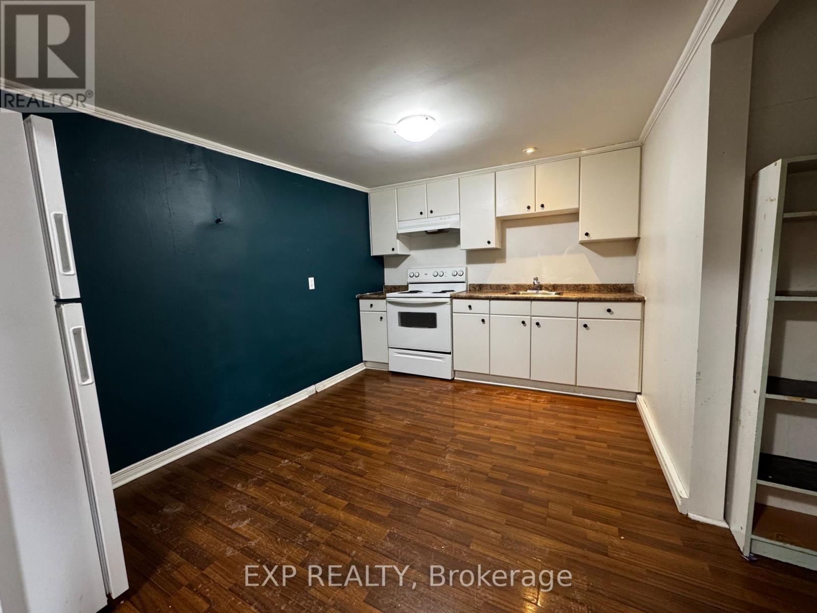 A kitchen with white appliances and wooden floors.