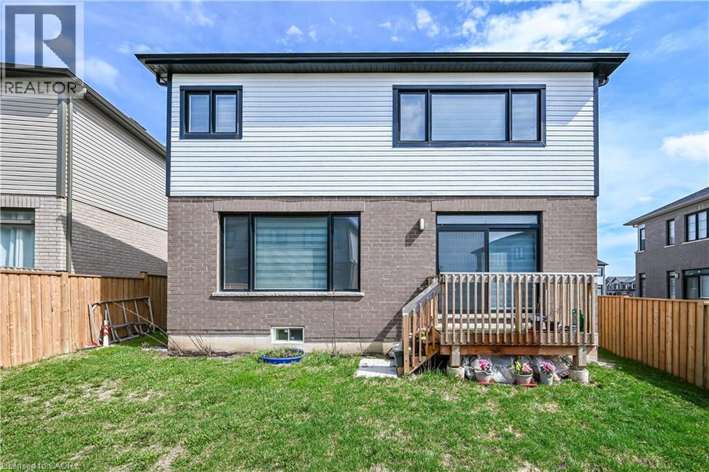 A two-story house with a grey and brown exterior and a wooden deck in the front yard.