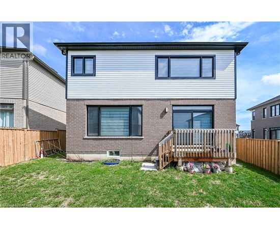 A two-story house with a grey and brown exterior and a wooden deck in the front yard.