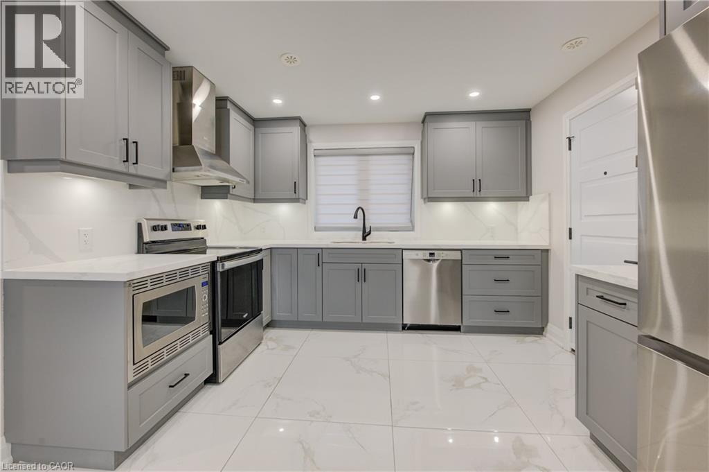A modern kitchen with grey cabinets and stainless steel appliances.