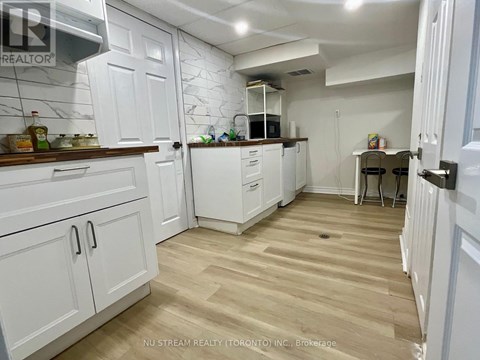 A kitchen with white cabinets and a wooden floor.