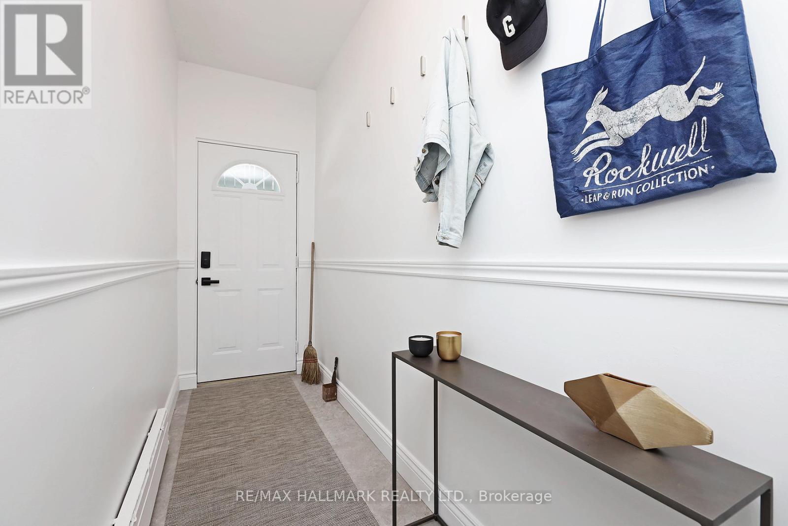 A hallway with a broom and a bag on the wall.