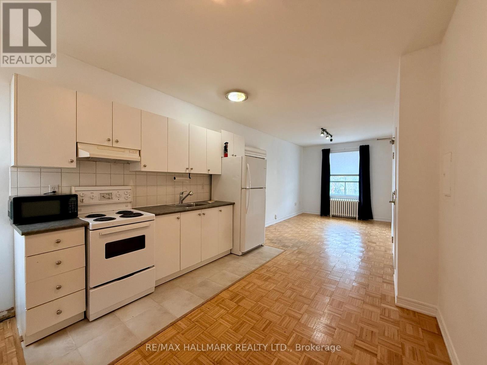 A kitchen with white cabinets and a black microwave.
