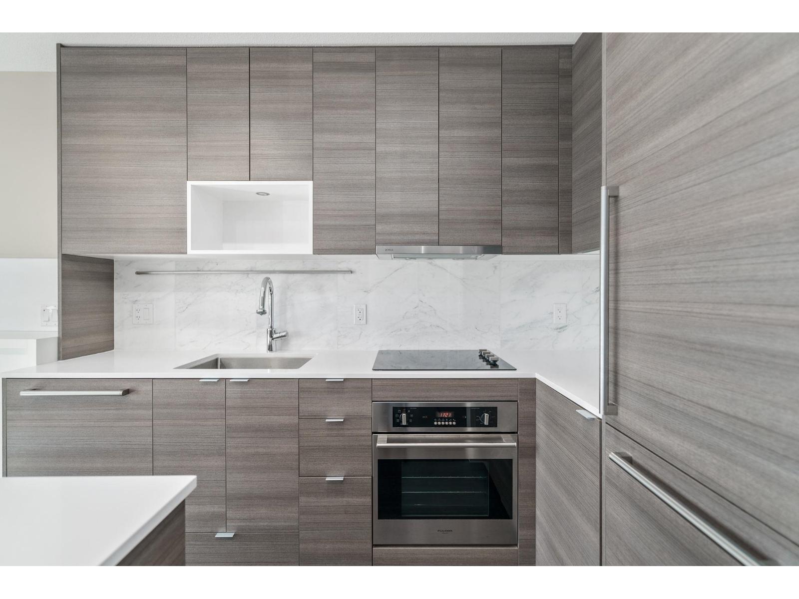 A modern kitchen with a stainless steel oven and a marble countertop.