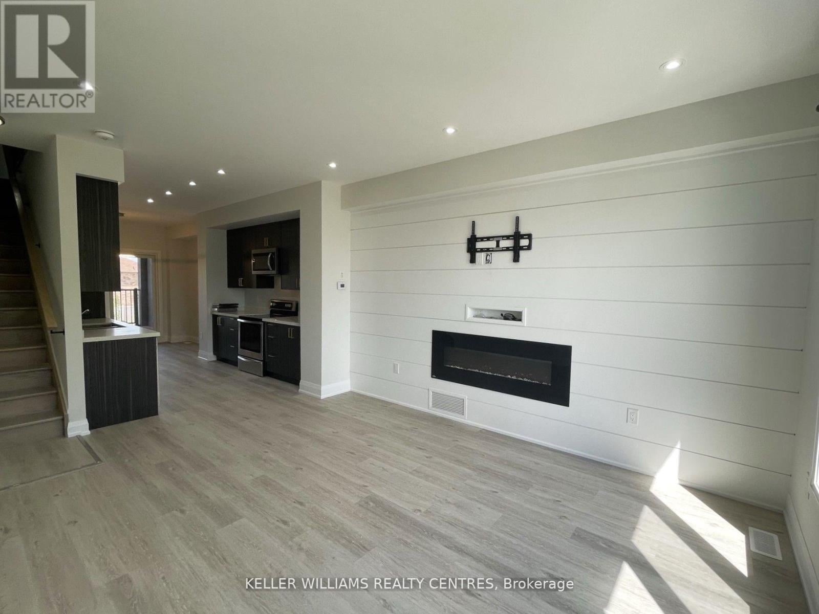 A spacious living room with wood flooring and a fireplace.